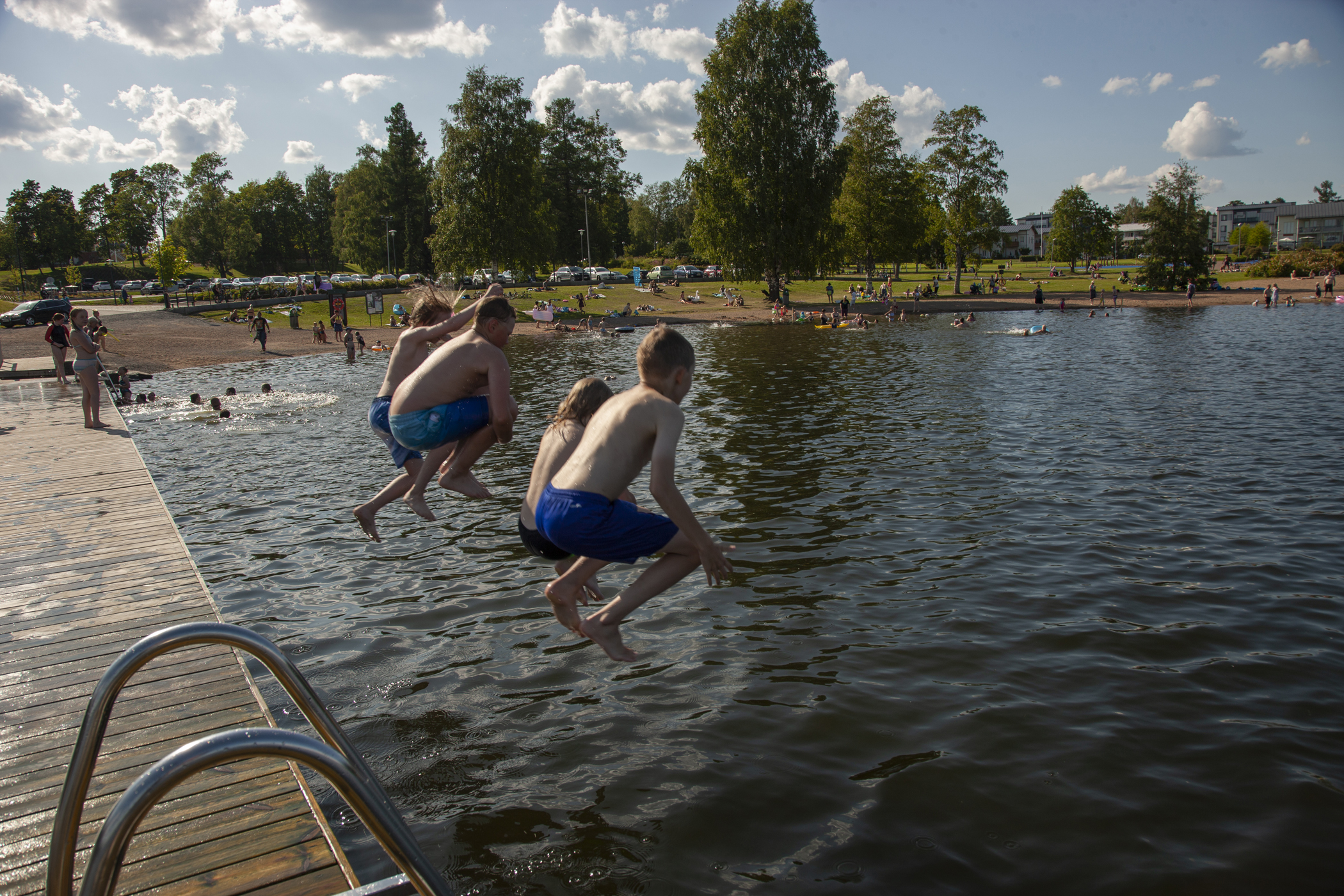 Pojat hyppäävät laiturilta järveen.